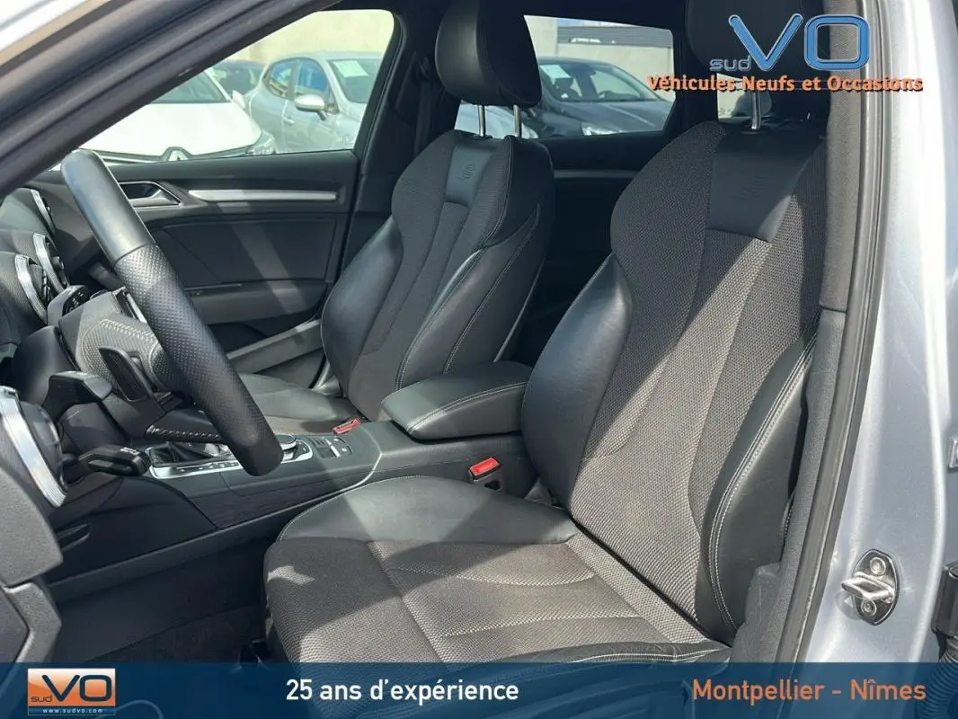 Intérieur de l'Audi A3 Sportback gris clair, vue côté gauche montrant sièges sport et volant multifonctions cuir perforé.