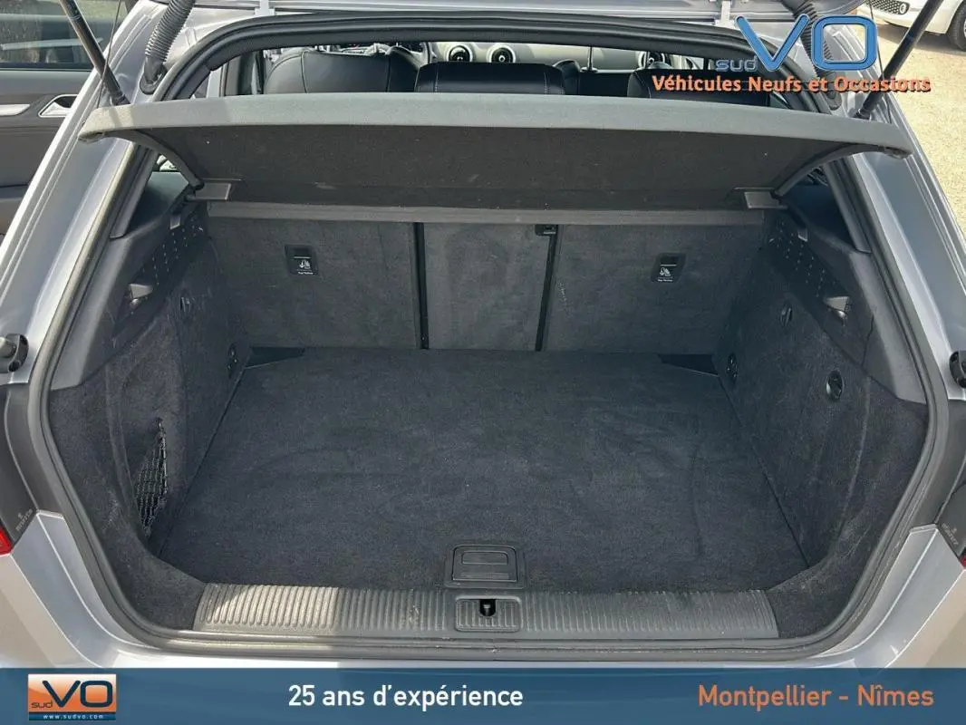Coffre ouvert vu de l'arrière d'une Audi A3 Sportback gris clair, montrant un espace de chargement propre et spacieux.