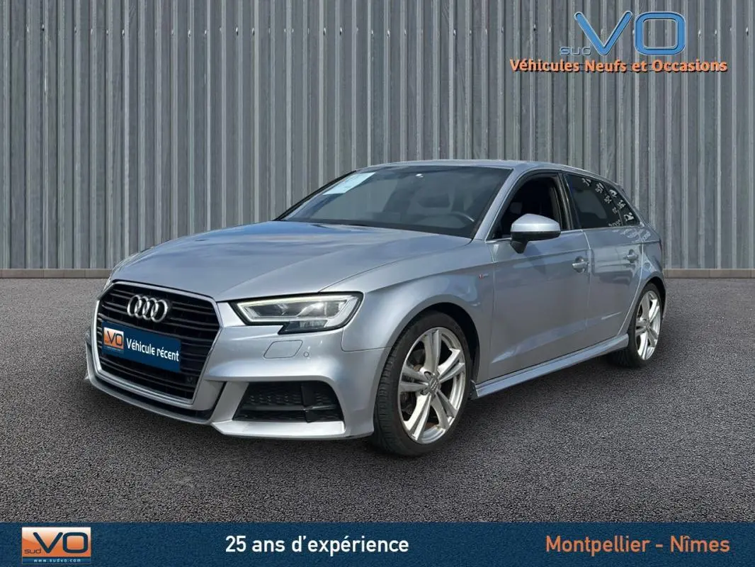 Audi A3 Sportback gris clair vue 3/4 avant droit avec jantes alliage et phares LED allumés.