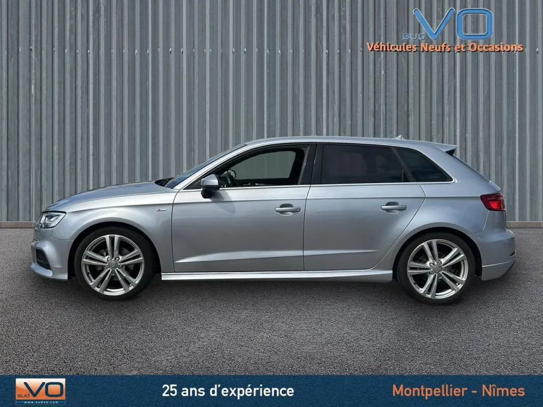 Profil côté gauche d'une Audi A3 Sportback gris clair de 2018 avec jantes alliage et châssis sport visible.