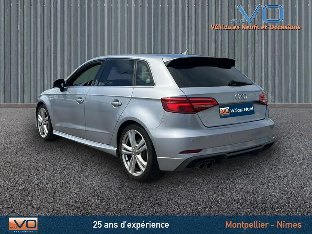 Audi A3 Sportback gris clair vue 3/4 arrière droit, avec jantes alliage et vitres teintées.
