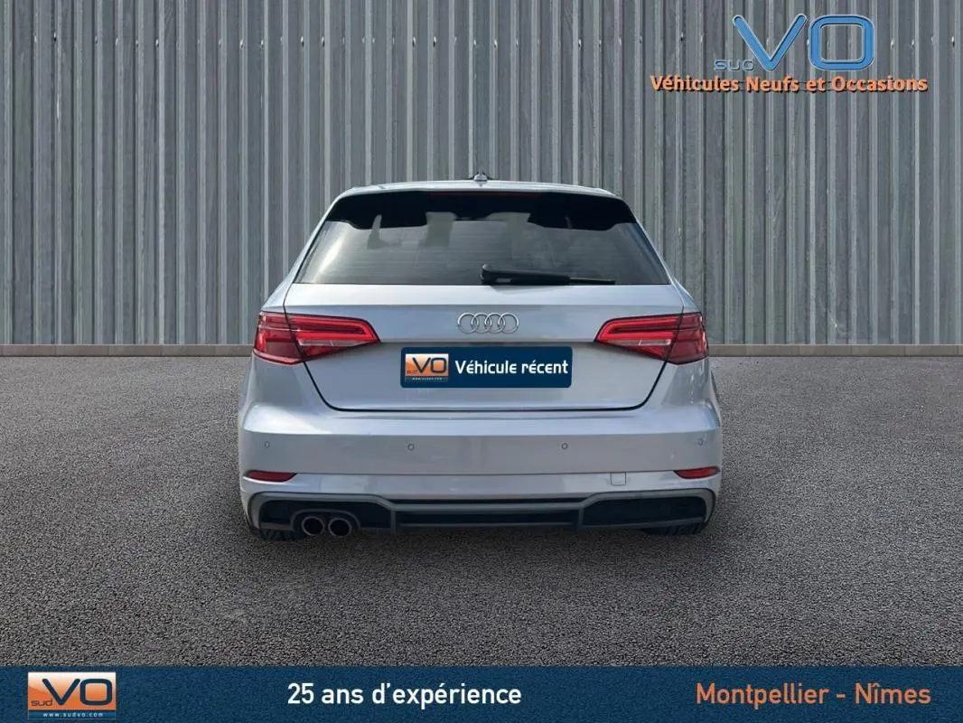 Vue arrière d'une Audi A3 Sportback gris clair de 2018 avec feux LED et double sortie d'échappement à gauche.