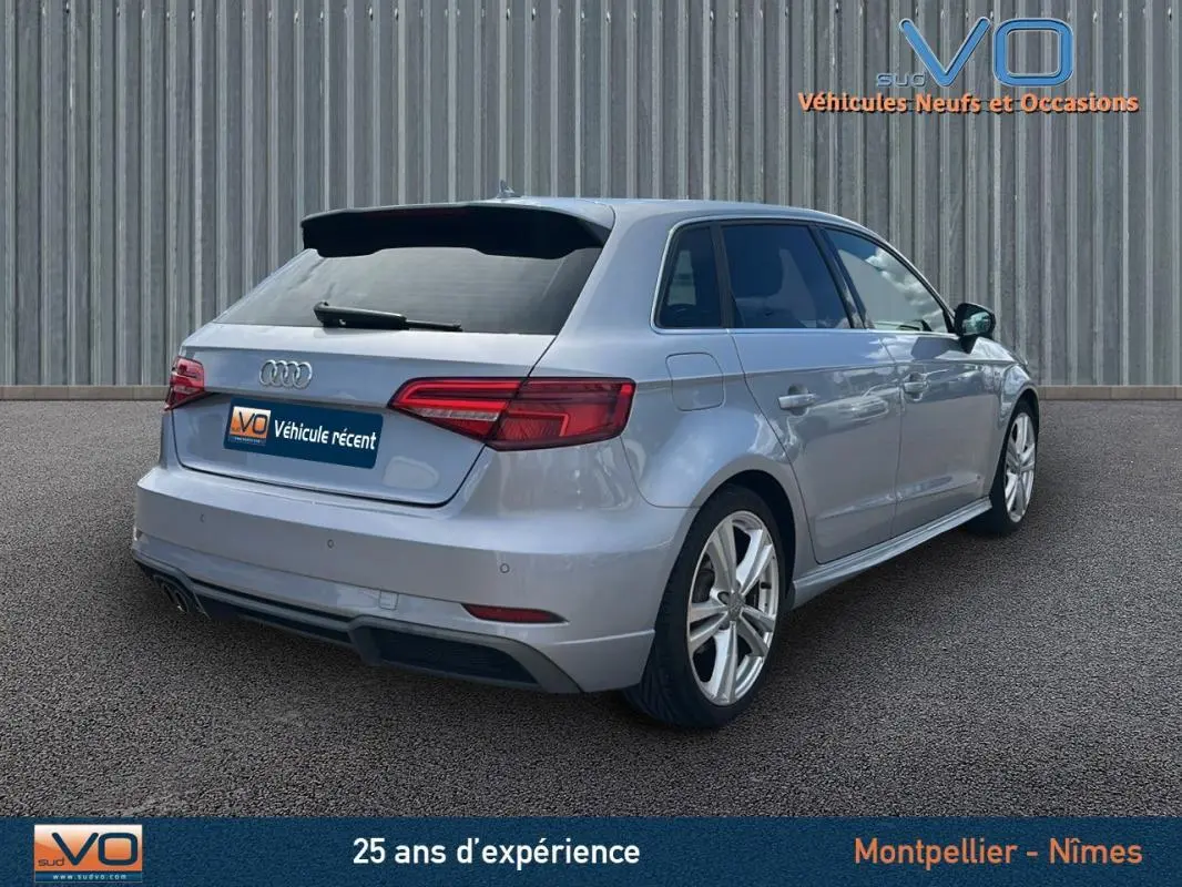 Audi A3 Sportback gris clair vue 3/4 arrière droit, avec jantes alliage et feux arrière LED distinctifs.