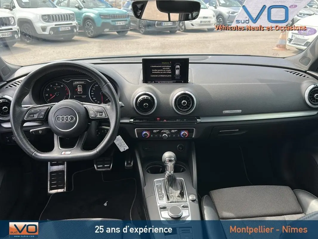 Vue intérieure avant de l'Audi A3 Sportback gris clair 2018, volant sport multifonctions et console centrale avec écran intégré.