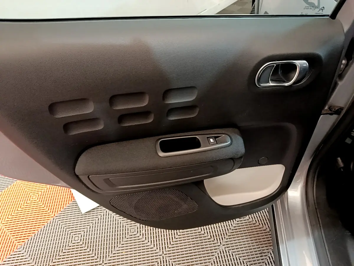 Gros plan sur la portière avant droite gris clair de la Citroën C3 2019 avec poignée chromée et commande de vitre électrique.