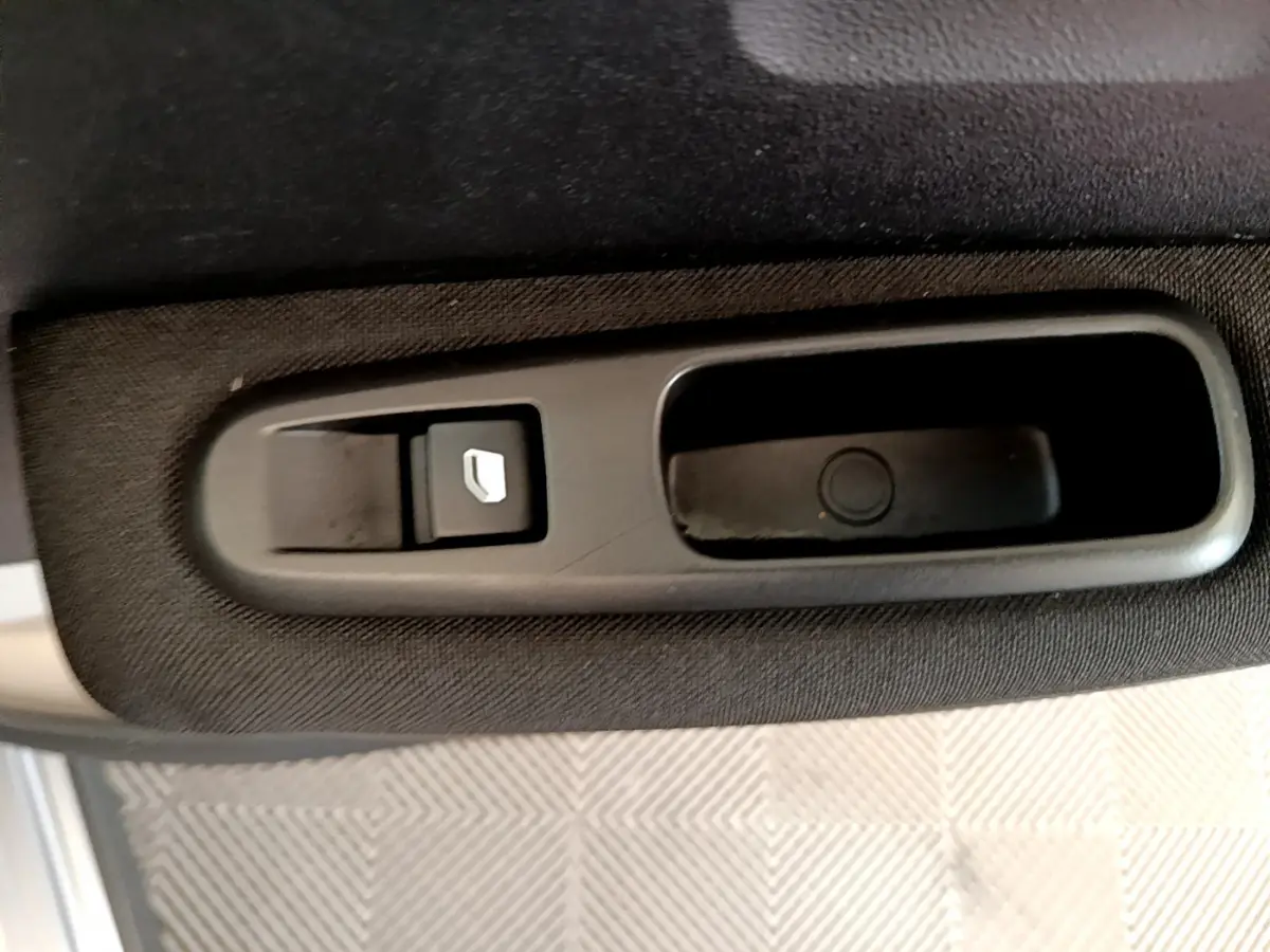 Détail de la commande de lève-vitre électrique sur la porte intérieure côté conducteur d'une Citroën C3 gris clair 2019.
