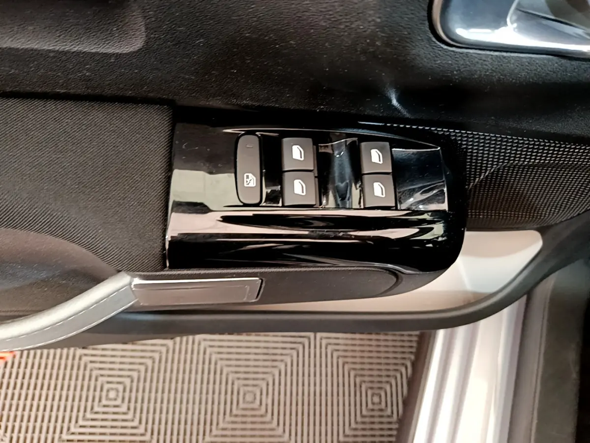 Vue rapprochée des commandes de lève-vitres sur la porte côté gauche d'une Citroën C3 gris clair de 2019.