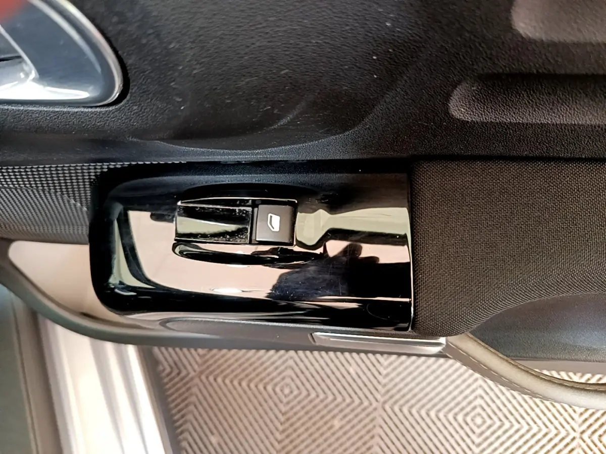 Gros plan sur le bouton de commande de la vitre côté conducteur de la Citroën C3 gris clair de 2019.