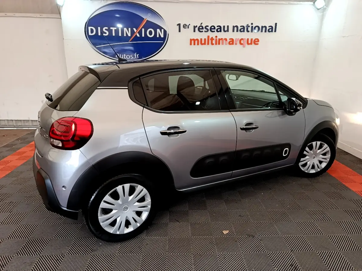 Citroën C3 gris clair vue de profil côté droit, avec toit noir et protections latérales noires distinctives.