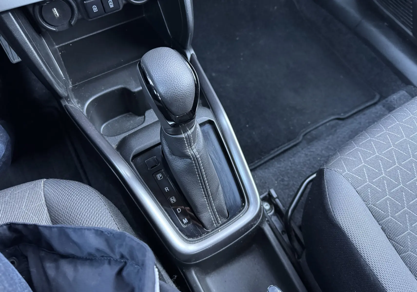 Le levier de vitesse automatique en cuir noir de la Suzuki Swift 2024, vue rapprochée de la console centrale intérieure.