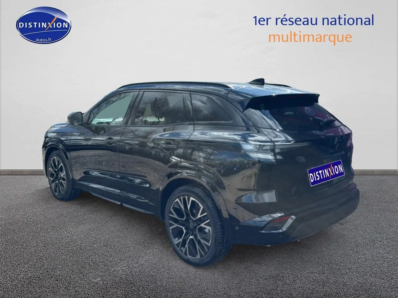 Vue 3/4 arrière droite du Renault Austral noir avec jantes alliage 20 pouces et barres de toit visibles.