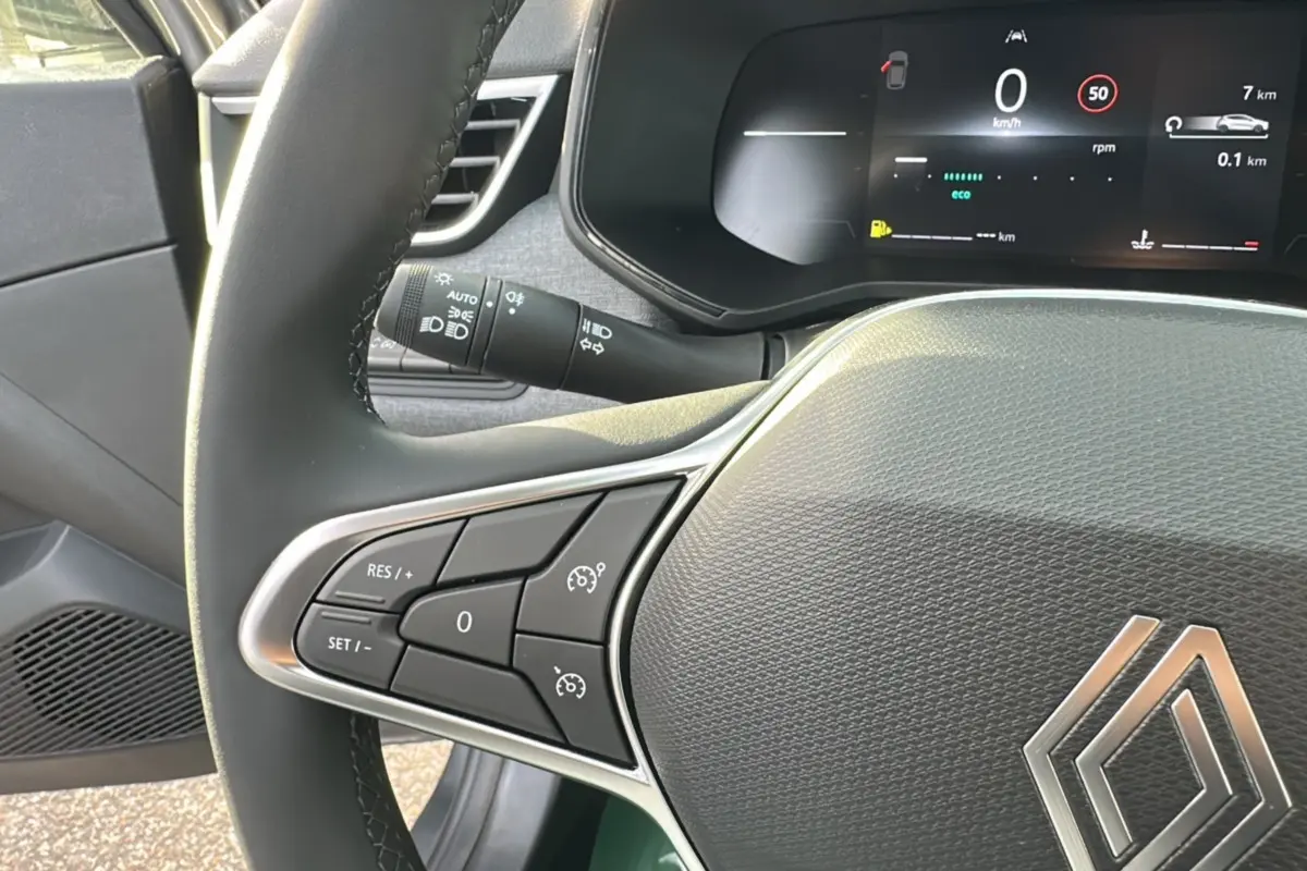 Gros plan sur le volant multifonctions cuir de la Renault Clio gris schiste, avec affichage numérique du tableau de bord.