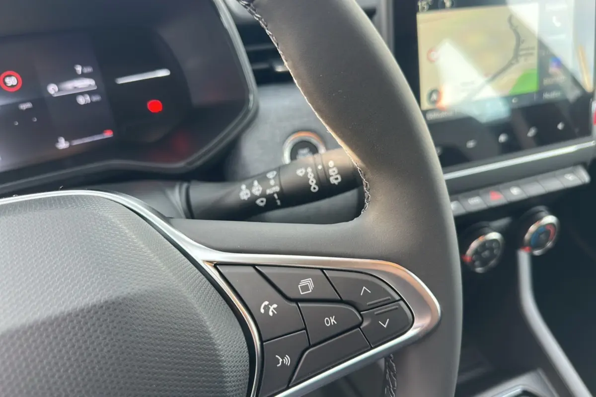 Gros plan sur le volant multifonctions en cuir de la Renault Clio DCI 100 Evolution, avec écran tactile et commandes au volant visibles.