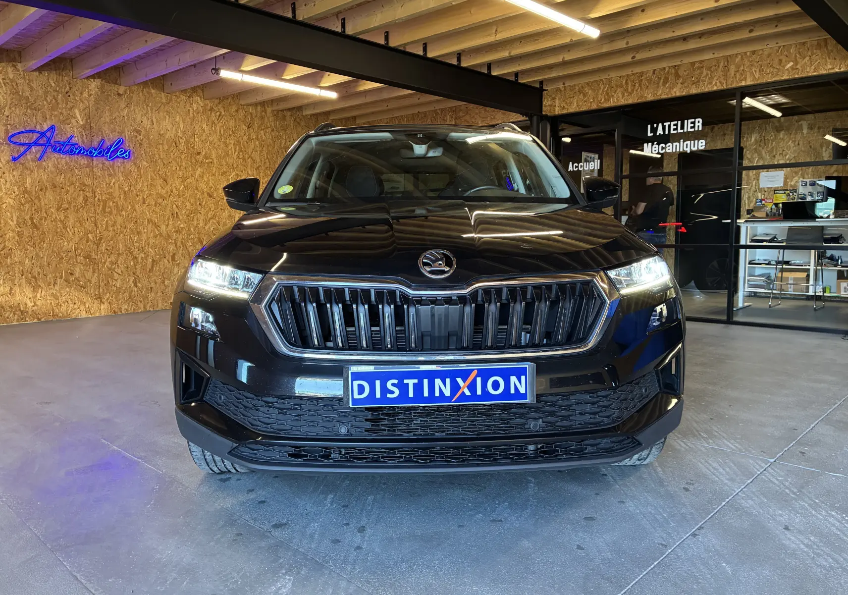 Vue frontale d'un Skoda Karoq noir 2024 avec calandre noire et contours chromés, phares allumés en intérieur.