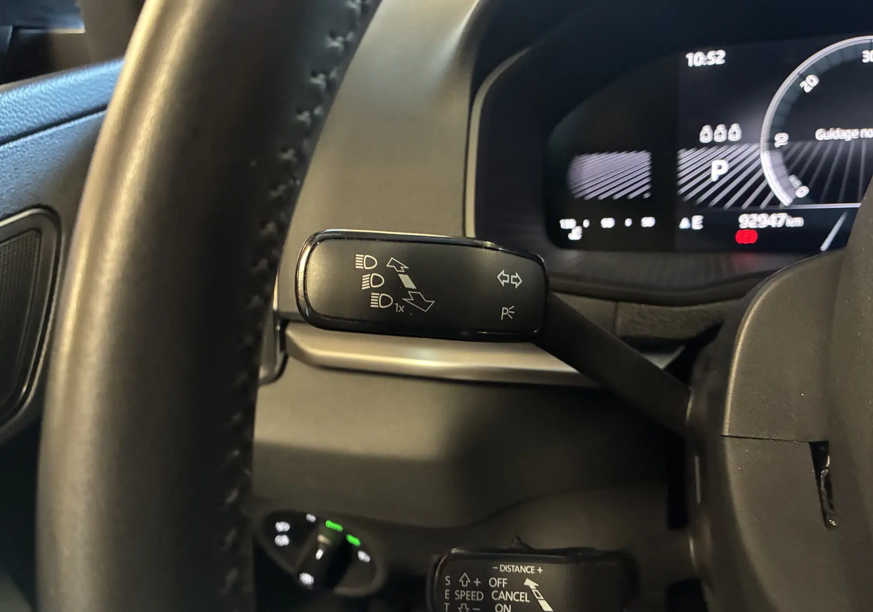 Gros plan sur la commande de clignotants et régulateur derrière le volant du Skoda Karoq noir, tableau de bord numérique visible.
