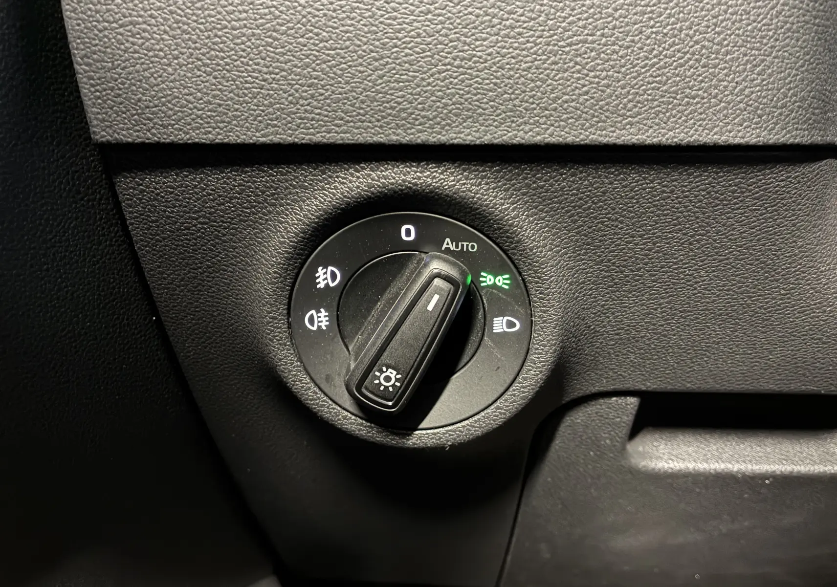 Gros plan sur le bouton de commande des phares du Skoda Karoq 2024, avec réglage automatique activé.