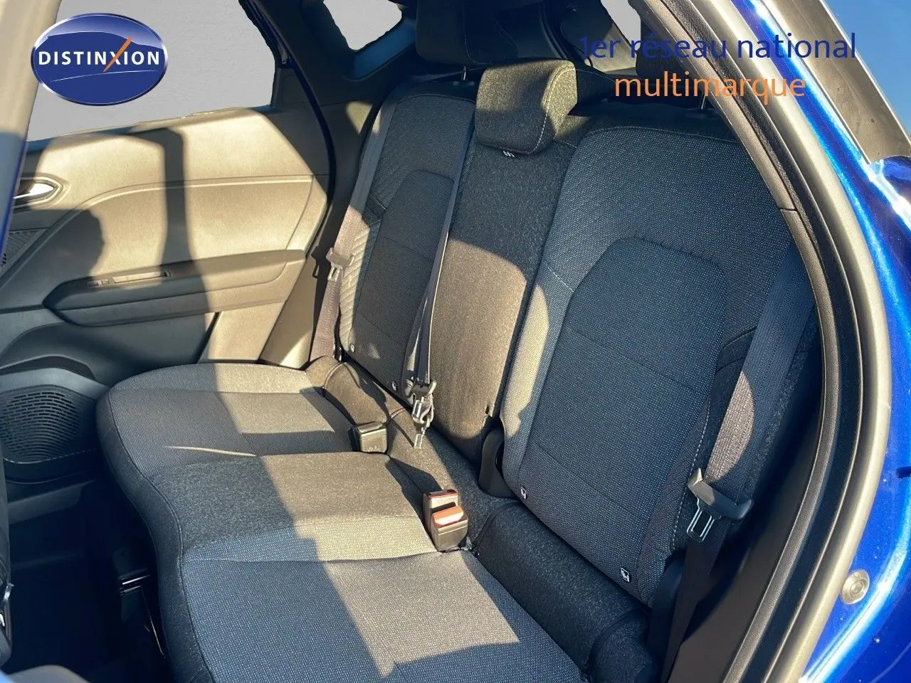 Vue latérale côté droit de l'habitacle arrière du Renault Captur bleu iron metal avec sièges tissu gris.