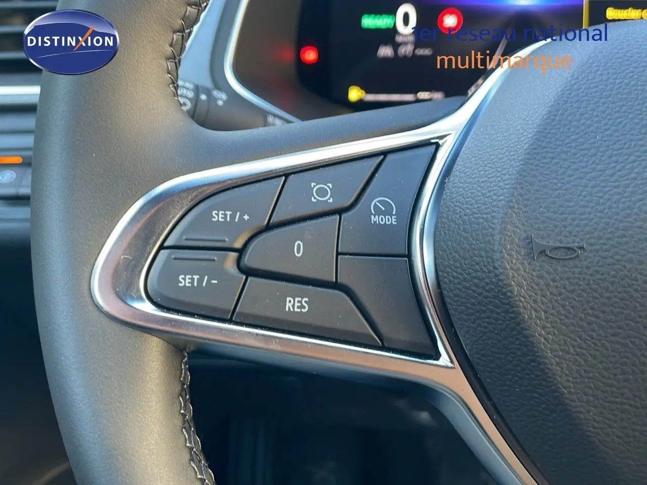 Gros plan sur les commandes au volant du Renault Captur E-Tech bleu Iron Metal avec toit noir, affichage numérique en arrière-plan.