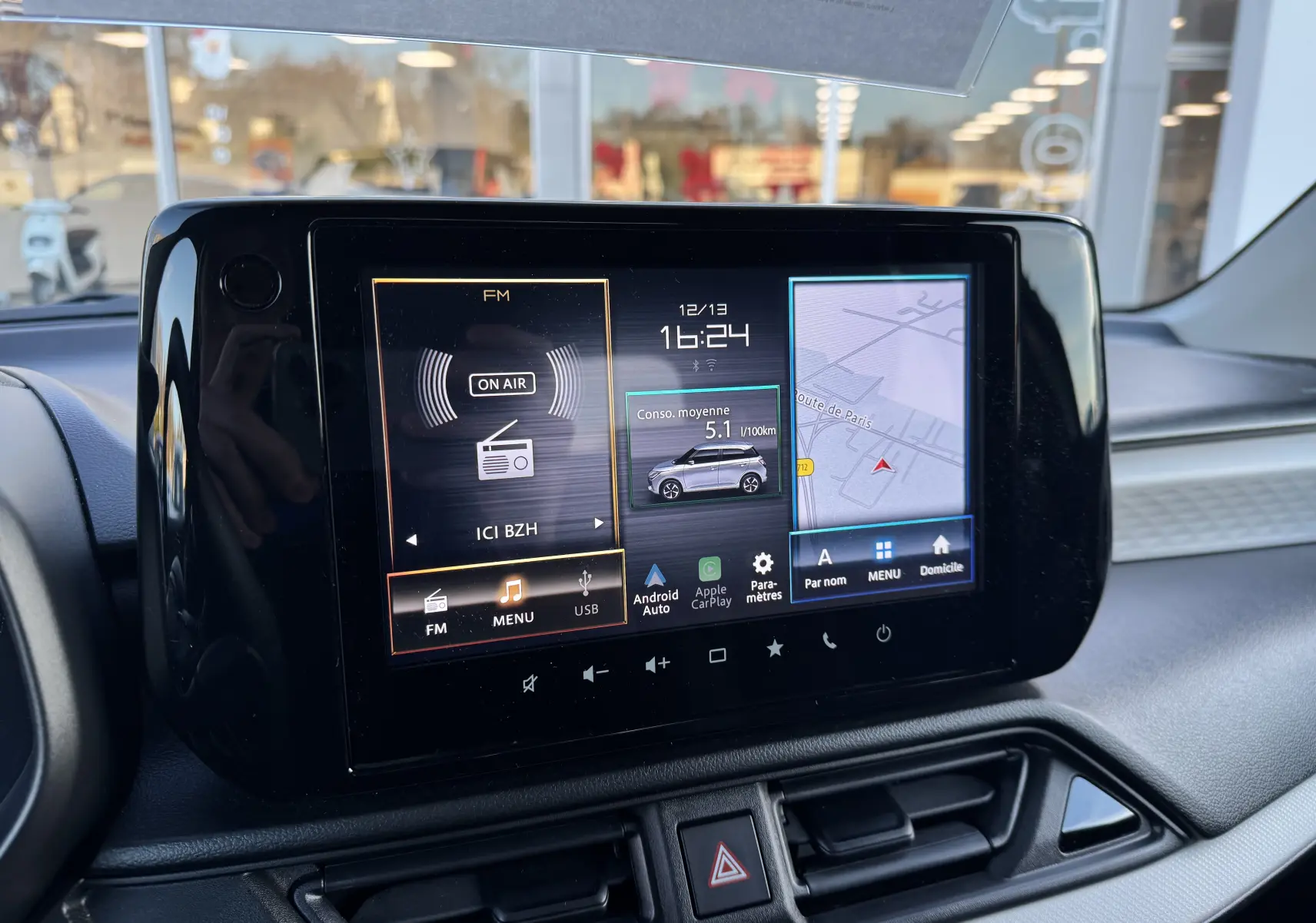 Écran tactile central de la Suzuki Swift 1.2 Privilege Hybrid 2025 affichant radio, consommation et navigation.