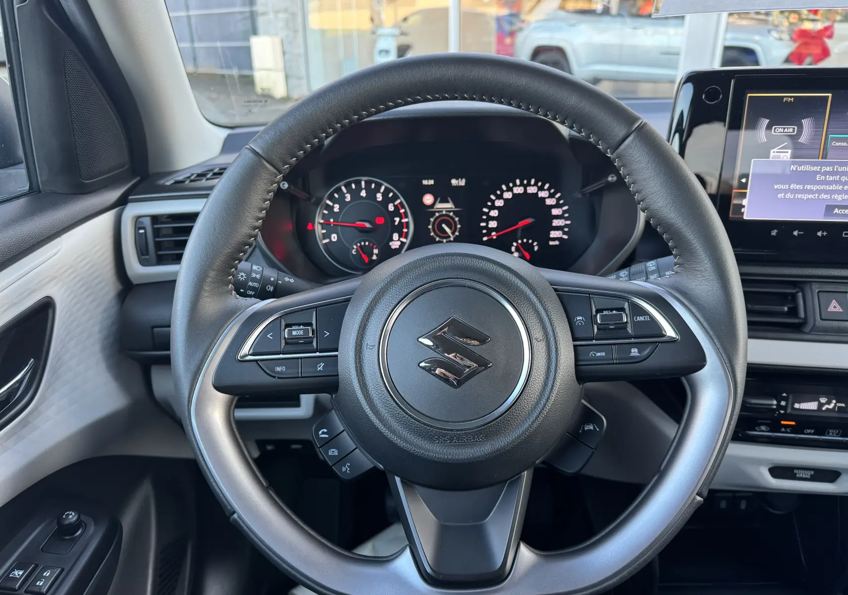 Vue rapprochée du volant cuir noir de la Suzuki Swift 1.2 Privilège Hybrid 2025 avec tableau de bord et écran tactile.