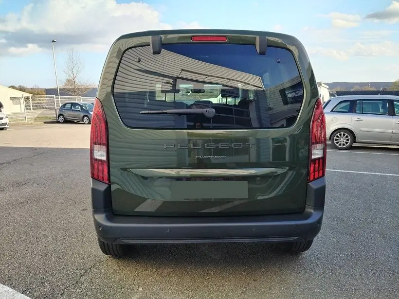 Vue arrière d’un Peugeot Rifter 2025 vert Srikka avec hayon et feux arrière verticaux dans un parking extérieur.