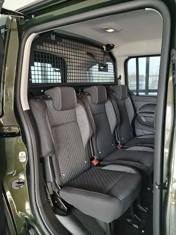 Vue intérieure côté droit des trois sièges arrière noirs du Peugeot Rifter 2025 en Srikka Green avec séparation grillagée.