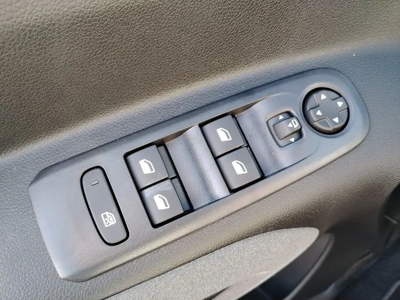 Commande des vitres électriques et réglage des rétroviseurs sur la porte intérieure noire du Peugeot Rifter 2025.