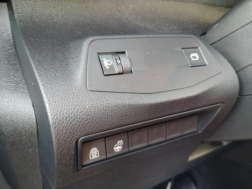 Gros plan sur les commandes noires côté gauche du tableau de bord du Peugeot Rifter 2025, avec boutons de réglage et verrouillage.