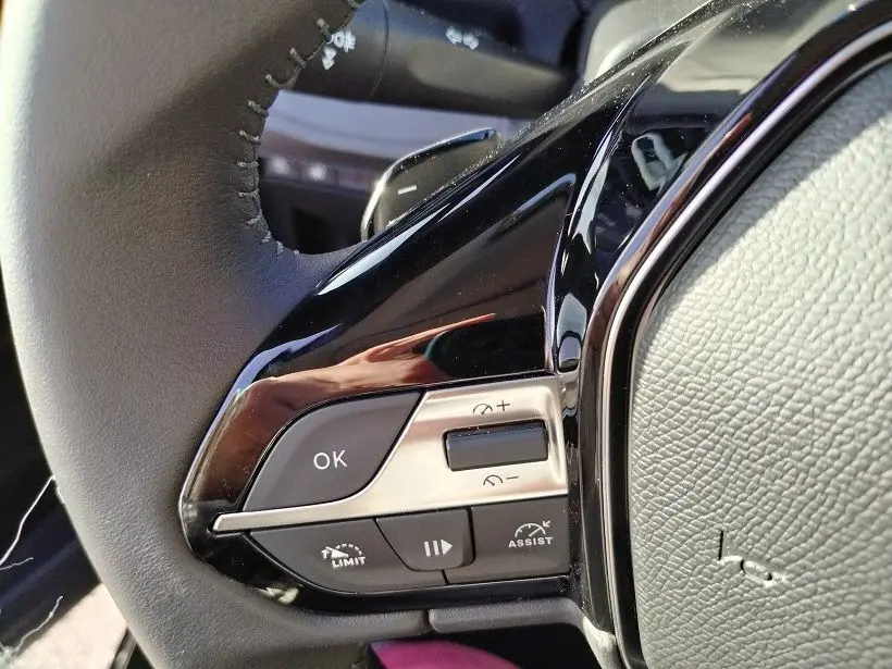 Gros plan sur les commandes gauche du volant noir du Peugeot Rifter 2025, avec boutons de régulateur et finition brillante.