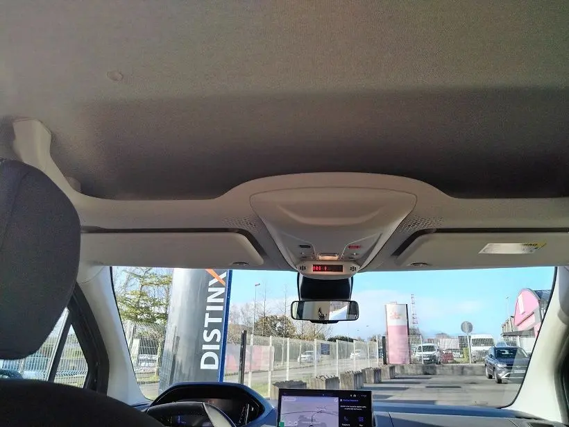 Vue intérieure avant du Peugeot Rifter 2025 avec tableau de bord et rétroviseur central, ciel de toit clair visible.