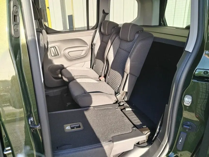 Vue intérieure côté droit du Peugeot Rifter 2025 vert Srikka, montrant les sièges arrière en tissu avec un siège rabattable.