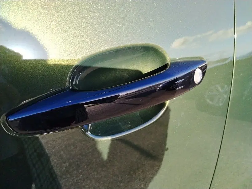 Poignée de porte noire en gros plan sur la portière côté gauche d’un Peugeot Rifter 2025 vert Srikka.