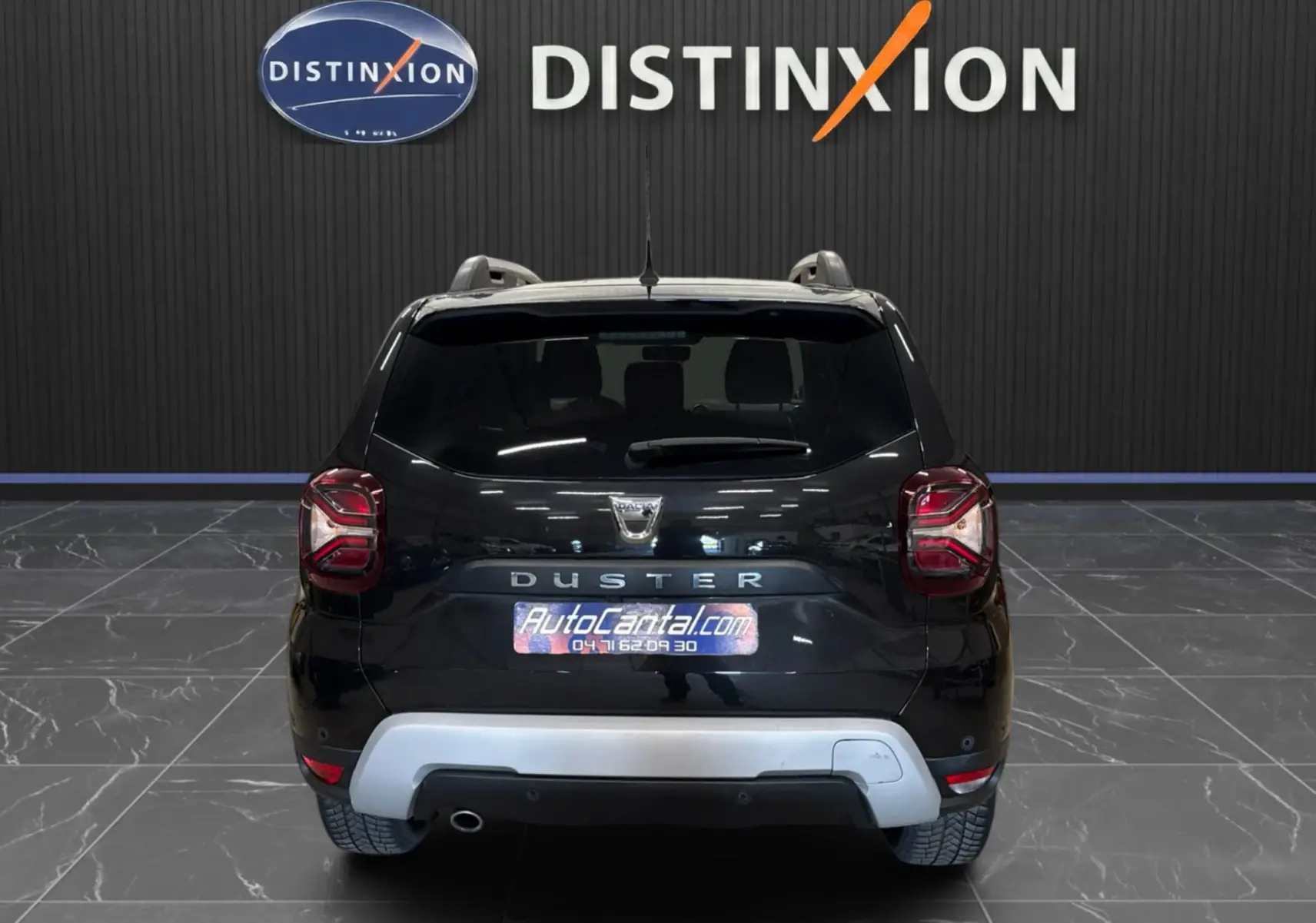 Vue arrière d'un Dacia Duster noir 2022 avec logo et plaque AutoCantal dans un showroom intérieur.