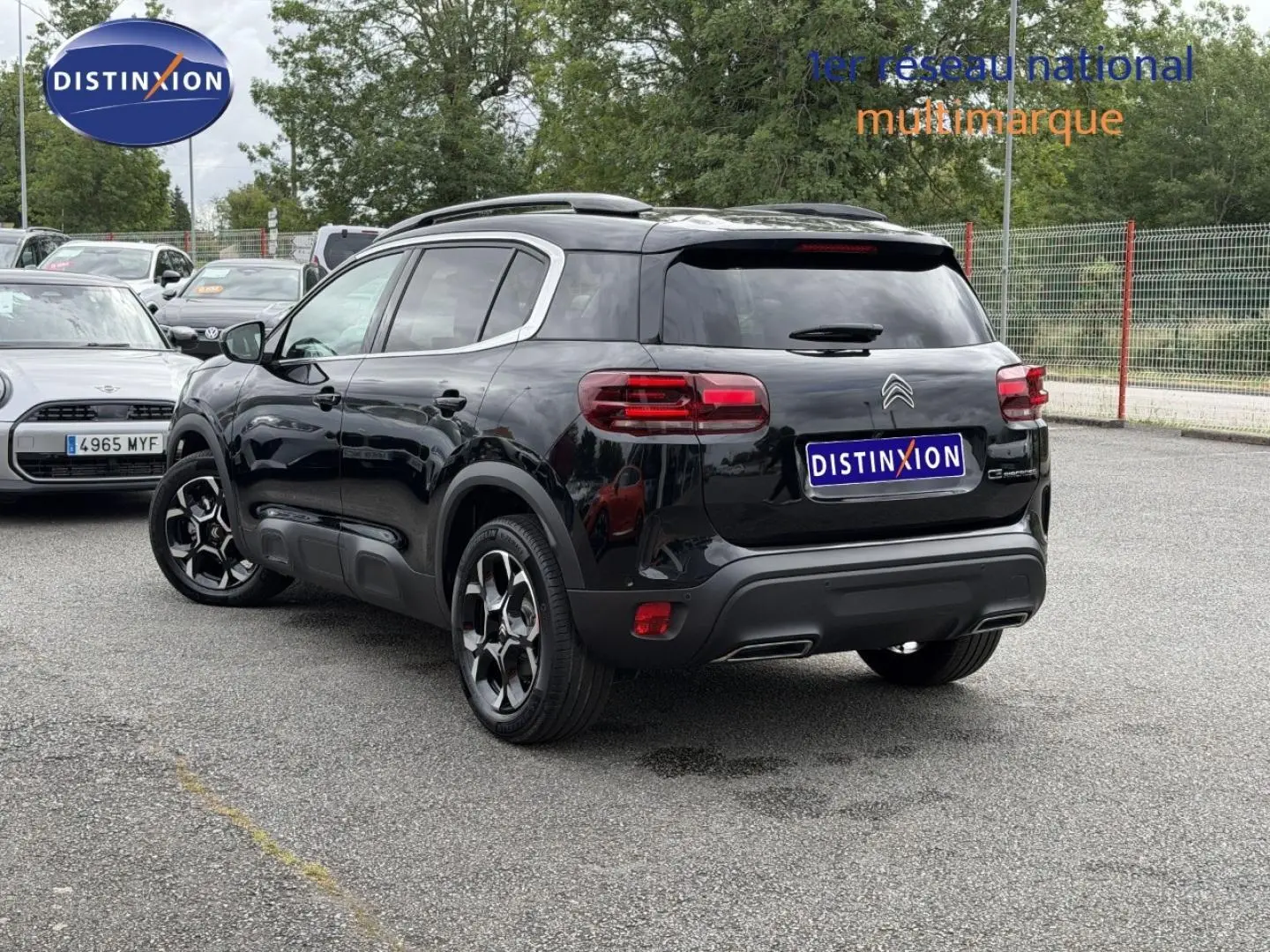 Vue 3/4 arrière droite du Citroën C5 Aircross noir Perla Nera avec barres de toit et jantes alu distinctives.