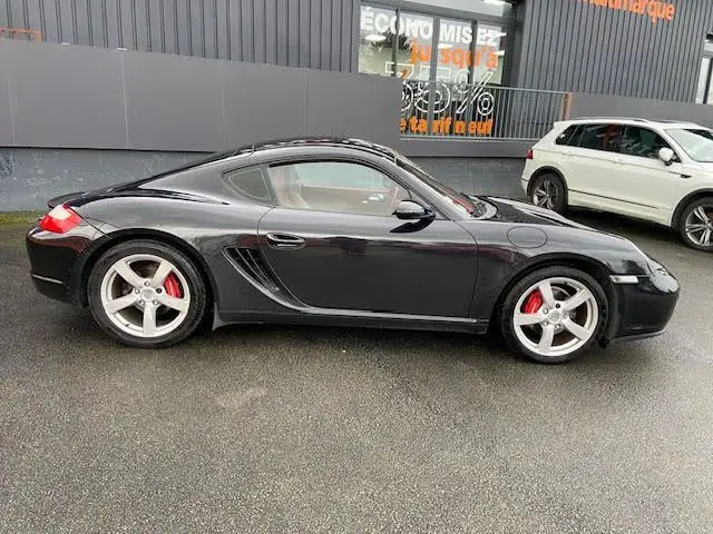 Profil côté gauche d'une Porsche Cayman noire 2008 avec jantes argentées et étriers de frein rouges.