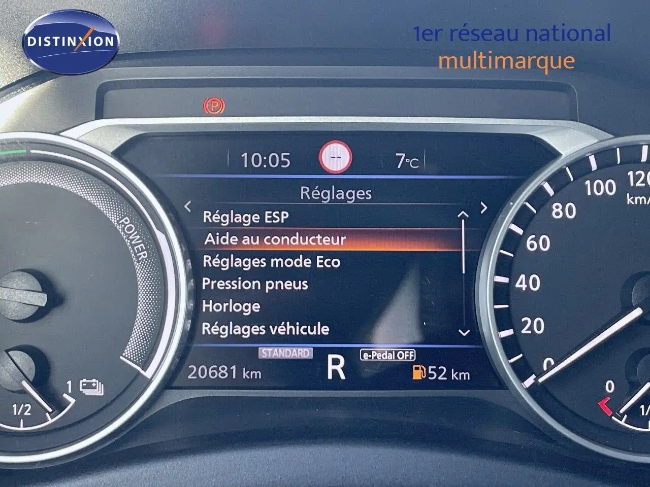 Tableau de bord numérique du Nissan Juke gris squale métal 2024 affichant les réglages et la vitesse en marche arrière.