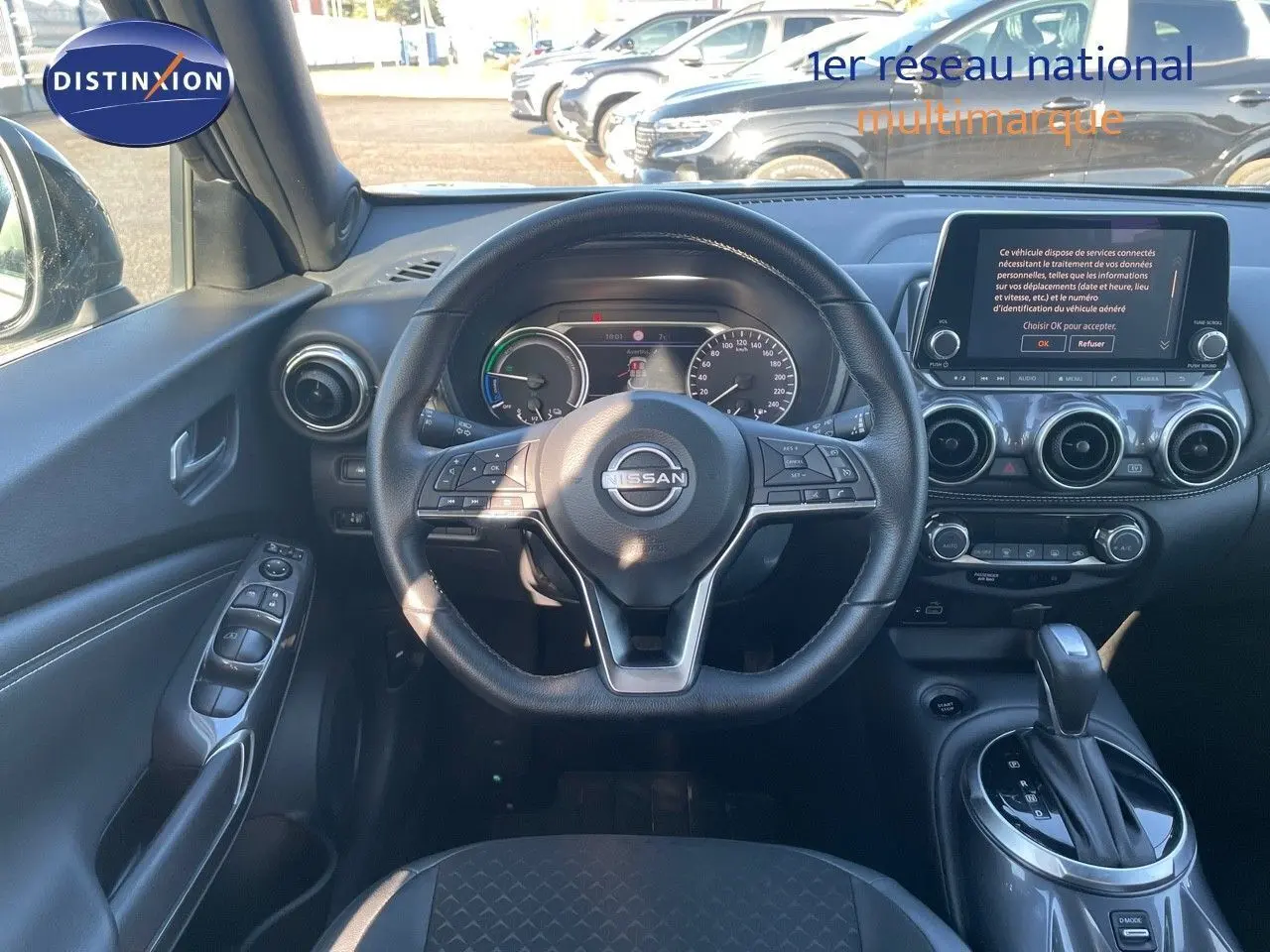 Vue intérieure du poste de conduite du Nissan Juke 2024 gris, avec volant multifonction et écran tactile central.