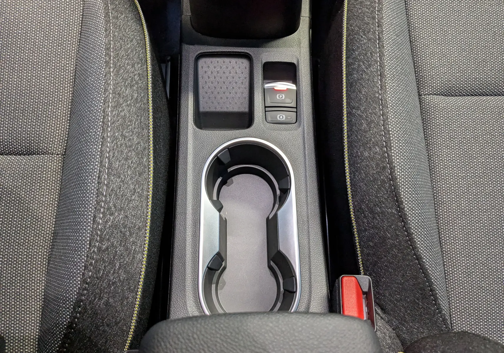 Vue rapprochée de la console centrale du Renault Captur E-Tech 2025, avec porte-gobelets et sièges gris à surpiqûres jaunes.