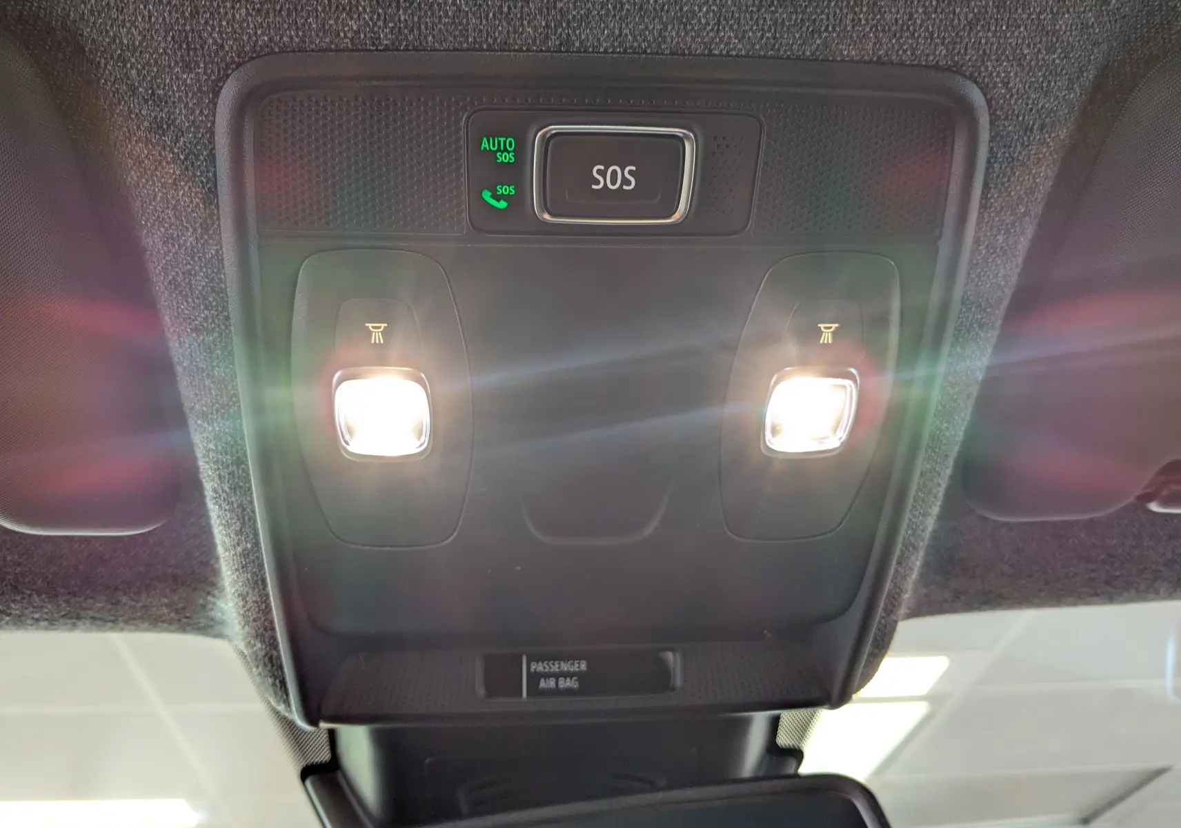 Vue en contre-plongée du plafonnier intérieur du Renault Captur 2025 avec éclairages de lecture allumés et bouton SOS.