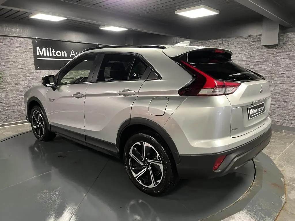 Vue 3/4 arrière droite du Mitsubishi Eclipse Cross gris métallisé avec jantes alliage bi-ton et toit noir en intérieur showroom.