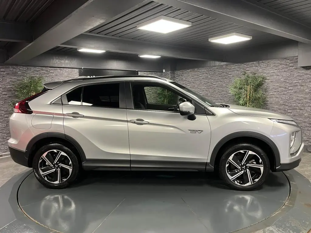Profil droit du Mitsubishi Eclipse Cross gris métallisé 2022 hybride rechargeable avec jantes alliage bi-ton et vitres surteintées.