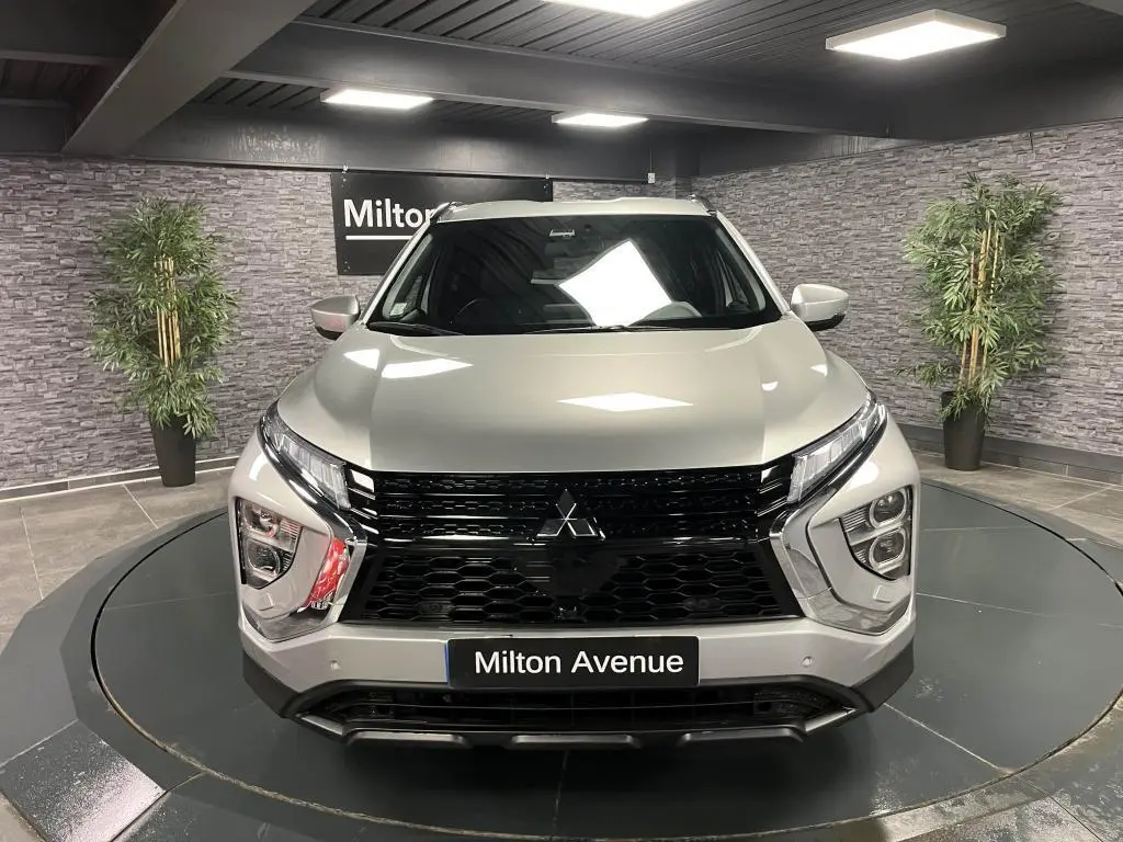 Vue frontale d'un Mitsubishi Eclipse Cross gris métallisé avec calandre noire et éclairage LED distinctif dans un showroom.