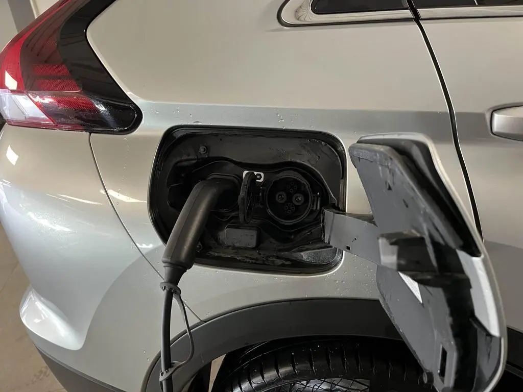 Prise de recharge branchée sur le côté gauche arrière d'un Mitsubishi Eclipse Cross gris métallisé 2022 hybride rechargeable.