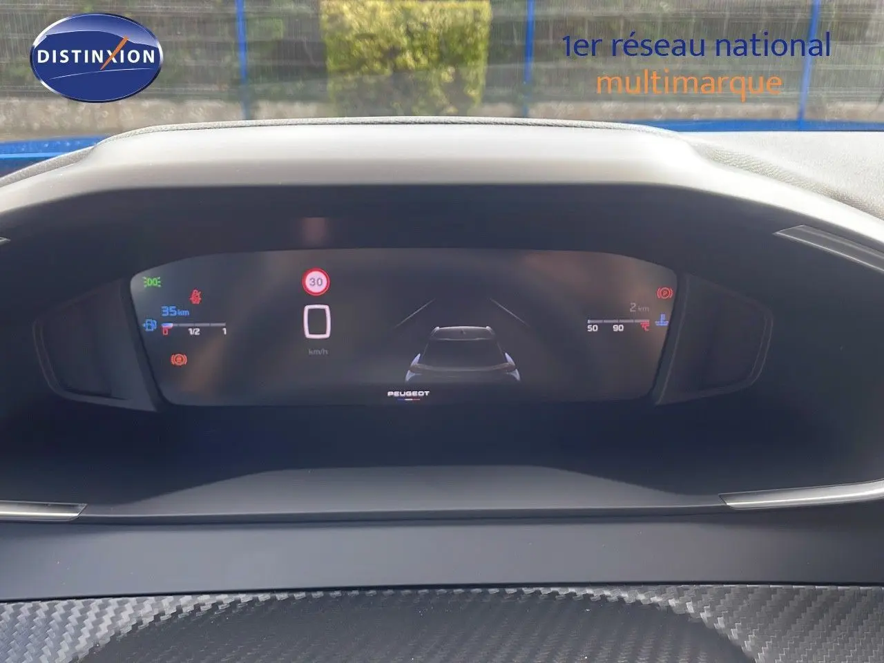 Vue rapprochée du tableau de bord numérique du Peugeot 2008 bleu Vertigo Metal, affichant la vitesse et l'autonomie.