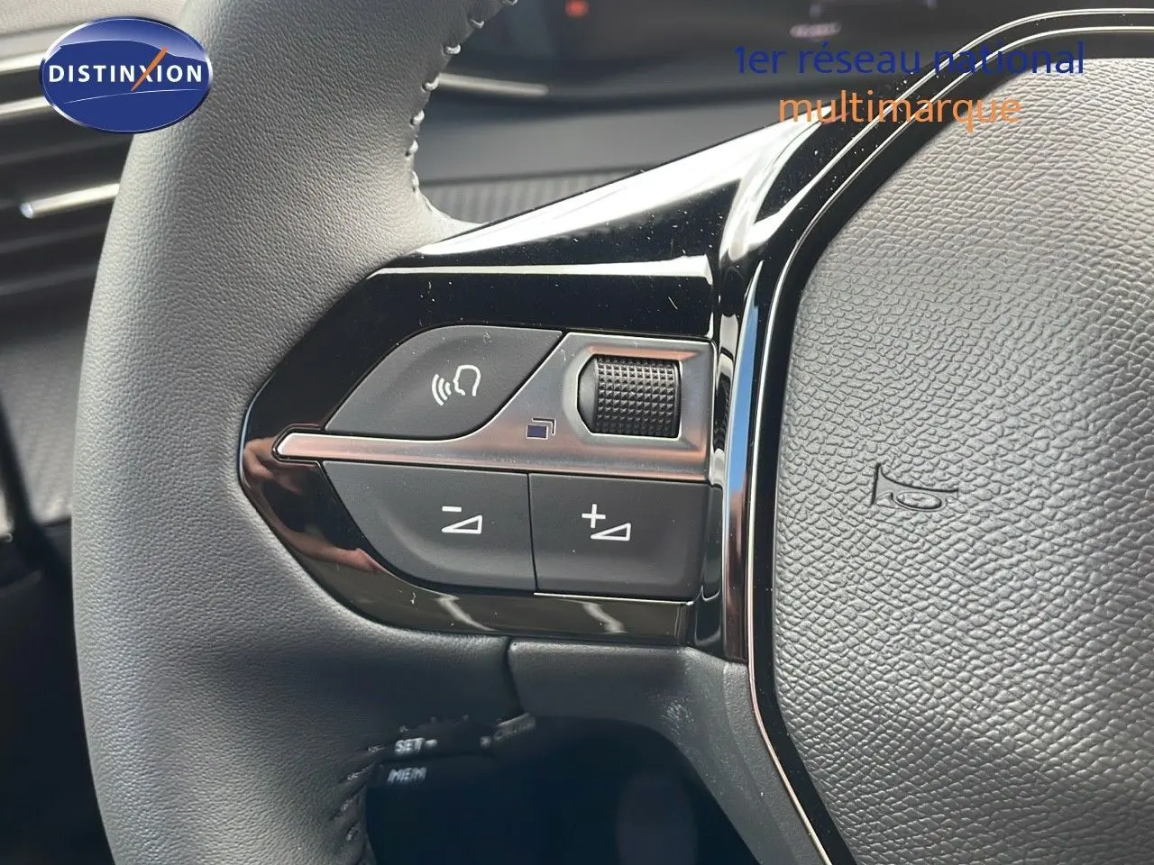 Gros plan sur les commandes gauche du volant du Peugeot 2008 bleu Vertigo Metal, montrant les boutons de volume et appel.