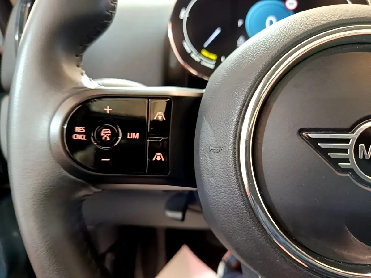 Gros plan sur le volant cuir noir du MINI COUNTRYMAN Cooper SE avec commandes de régulateur adaptatif côté gauche.