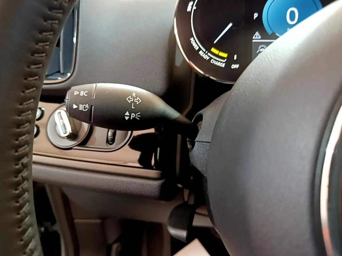 Gros plan sur la manette de clignotant noire côté gauche du volant cuir d’un MINI Countryman vert hybride 2023.