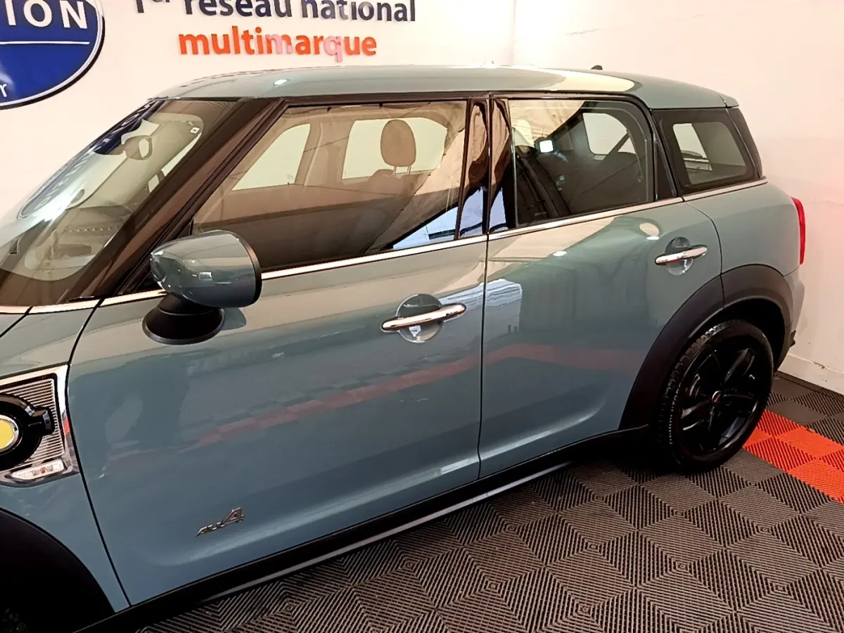 Vue latérale côté gauche d'un MINI Countryman hybride rechargeable vert avec toit blanc et jantes noires.