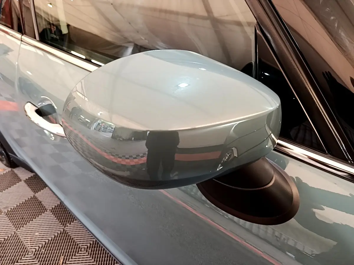 Rétroviseur côté gauche vert métallisé du MINI COUNTRYMAN Cooper SE 2023 avec carrosserie et poignée visibles.