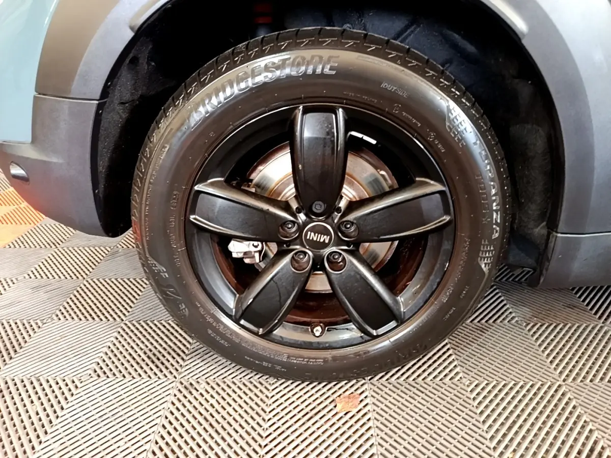 Gros plan sur la roue avant gauche noire avec jante cinq branches du MINI Countryman vert hybride 2023.